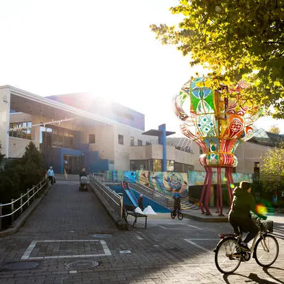 A large and colourful work of art in the courtyard of a large building. 