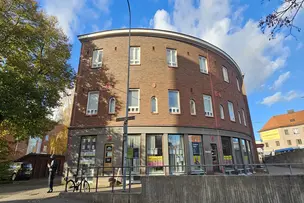 Stadin yhteisötalon tiiliseinäinen sisäänkäynti ja yhteisötalotoiminnan julisteita ikkunoissa.