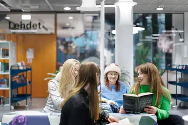 Neljä nuorta naista kirjastossa.