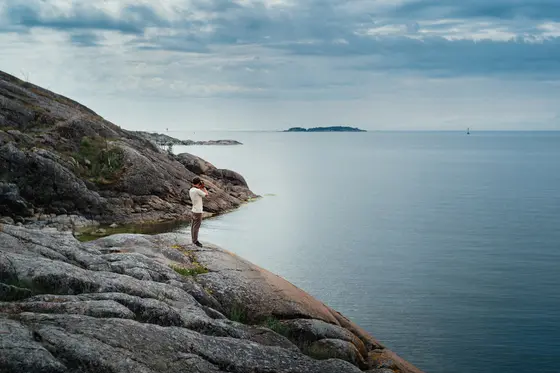 En man tittar ut mot havet i en skärgård.