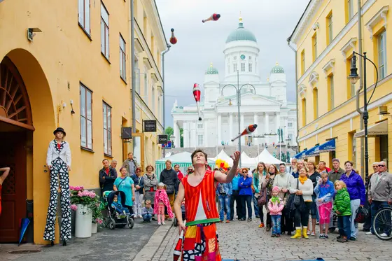 En publik som tittar på en jonglörs trick i Helsingfors torgkvarter.
