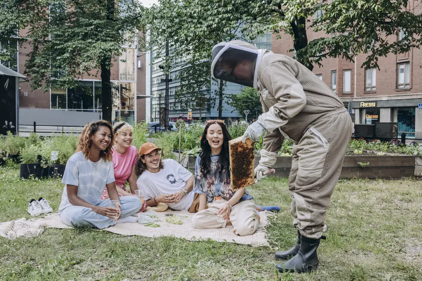 People watching a beekeeper in a park.