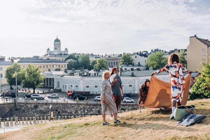 A group of people having a picnic, with the Helsinki Cathedral in the background.