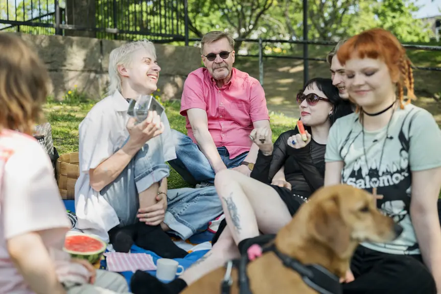 A family enjoying a day outdoors on a picnic blanket.