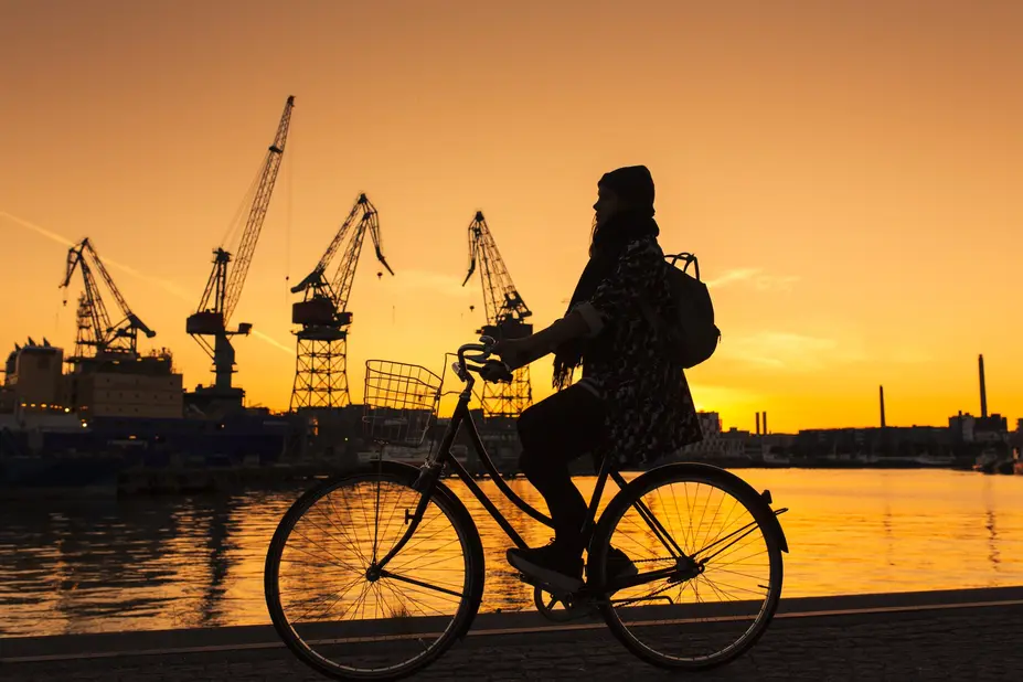 A woman bicycling during a sunset in Telakkaranta, Helsinki.