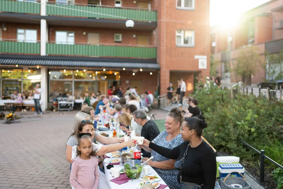 Smiling people dining outdoors in Malminkartano.