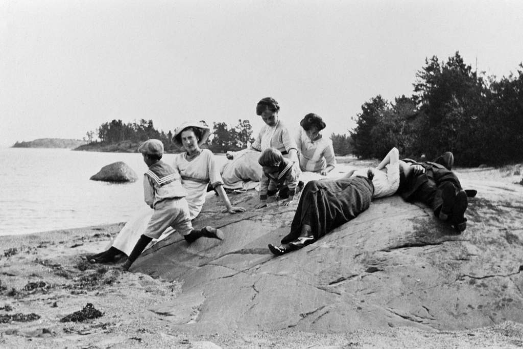 Naisia viettämässä päivää kalliolla kesällä mustavalkoisessa kuvassa.