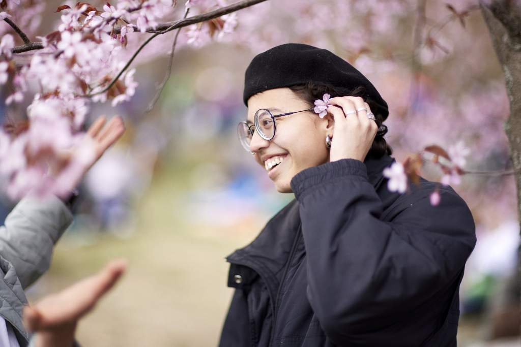 Naurava nainen kukkivien kirsikkapuiden alla