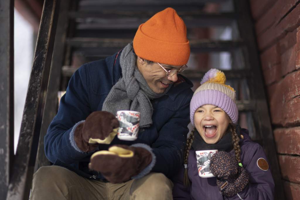 Isä ja tytär ulkona nauttimassa lämmintä juotavaa talvisena päivänä. .