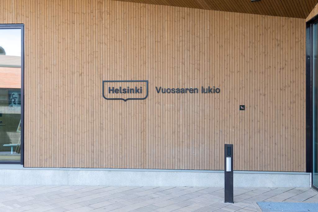 The entrance to Vuosaari general upper secondary school has a black Helsinki framed logo and the words Vuosaaren lukio.