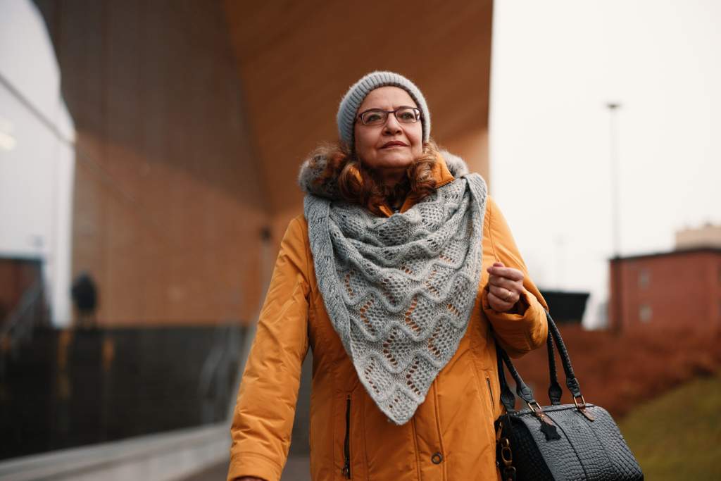 A woman walks in front of Oodi library in a cold autumn weather.