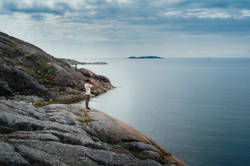 Man stands at the shore and looks at the sea in the Nordic archipelago.