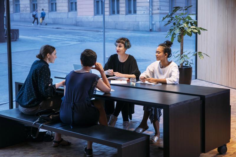 Neljä nuorta istuu ja keskustelee yliopiston kahvilassa.