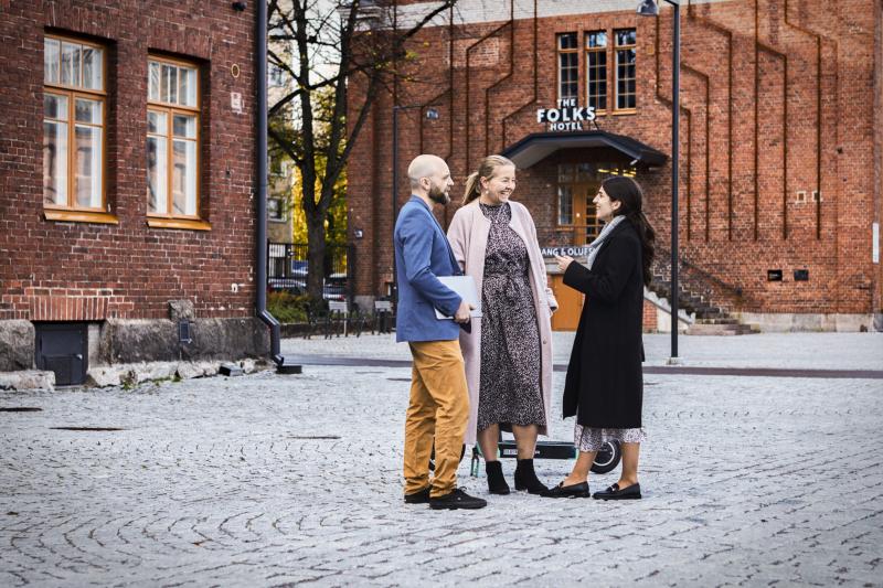 A man and two women discussing in industrial Vallila district.