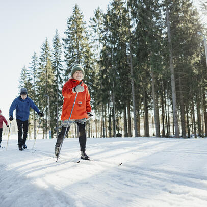 Valoisa tasainen latu ja hiihtäjiä.