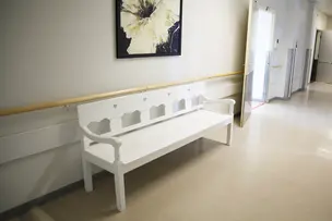 Käytävällä penkki ja oviaukko.