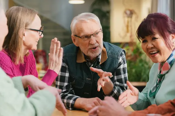 Eläkeläiset keskustelevat innokkaasti pöydän ääressä.