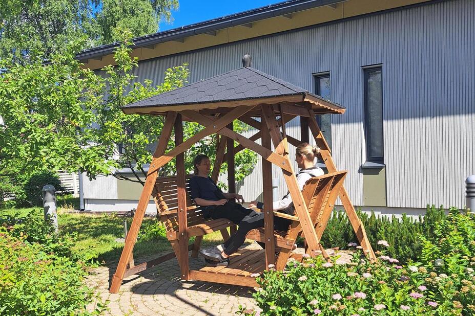 Två personer sitter i en gårdsgunga på en sommargård.