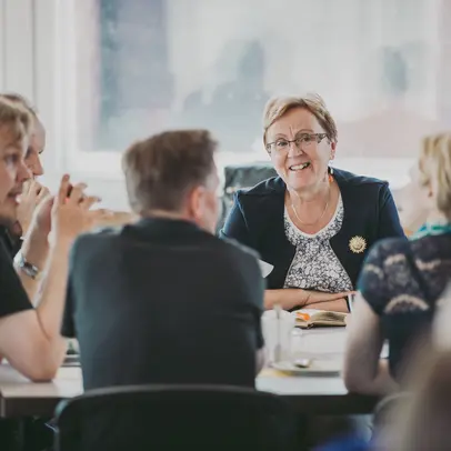 Ihmiset keskustelevat pöydän ääressä.