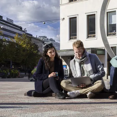 Ryhmä nuoria ihmisiä käyttää kannettavaa tietokonetta.