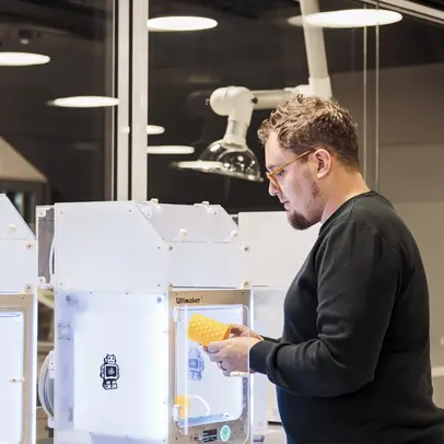 Henkilö käyttää 3D-tulostinta.
