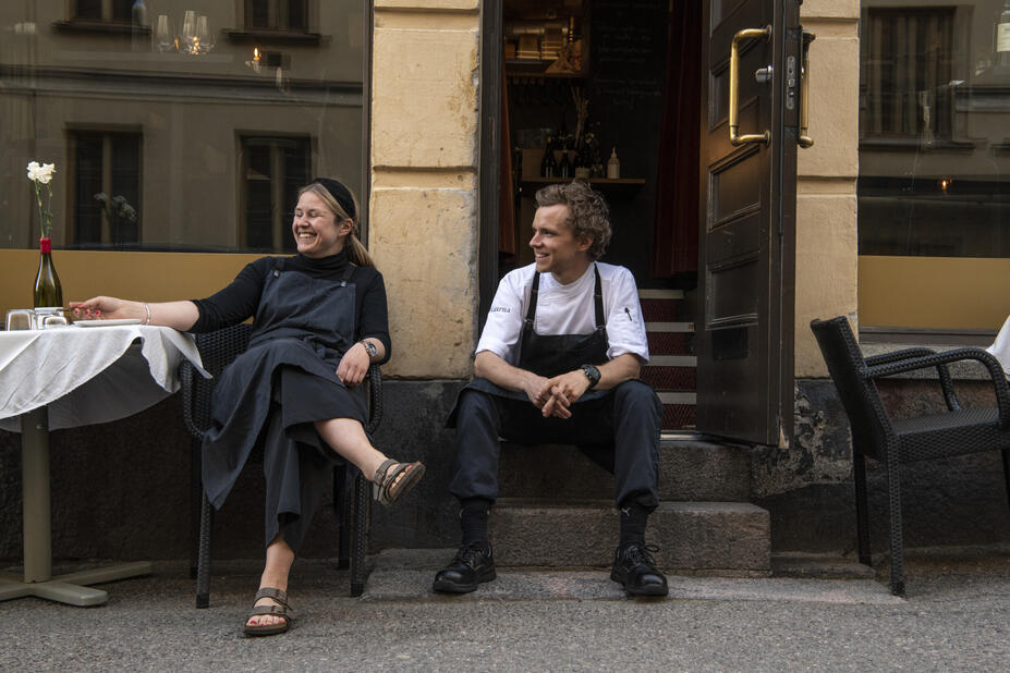 Two people sitting outside a restaurant.
